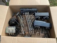 Box containing Lionel model 430 locomotive, two freight cars, and assorted metal track sections.