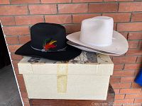Three cowboy hats placed on and next to a cardboard box