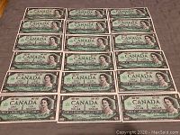 Top view of 20 uncirculated 1967 Canadian 1 dollar bills, laid out flat showing front side with Queen Elizabeth II portrait and centennial markings.