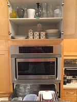 Cabinet with Fitz and Floyd dishware including cups, saucers, bowls, plates, and Serving pieces along with glass ovenware and plastic containers below
