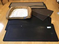 Overview of the Top Paw dog bed and 7 cushioned mats laid out on wood floor showing various sizes and colors.