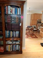 Full view of a four-shelf wooden bookcase with assorted hardcover books
