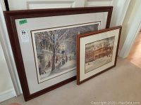 Two framed prints leaning against a door