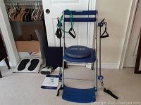 Front view of Chair Gym Twister showing blue seat, backrest, foot platform, and green resistance band attached