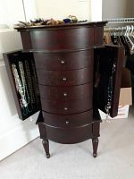 Front view of wood jewelry cabinet with side doors open showing necklaces on hooks