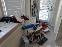 Photo showing assorted health and cleaning items including flags, massager, bath chair and boxes on carpeted floor