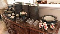 Overview of entire china set displayed on sideboard with plates, bowls, cups, saucers, pitchers, shakers