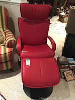 Front view of red vinyl armchair with matching footstool on black circular bases