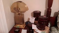 Brass table lamp on wooden surface next to two sets of round wooden jewelry boxes and a square wooden box