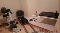 Room corner showing Everlast stationary recumbent bike, Pilates exerciser, and Current Concepts sliding exerciser.