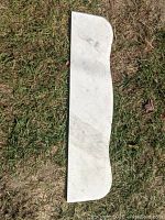 White marble shelf, top side showing natural veining and curved edge.