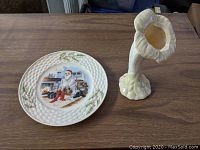 Full view of Irish Belleek Christmas plate and floriform vase on wooden surface