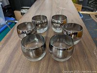 Front view of 6 Dorothy Thorpe silver fade roly poly double old fashioned tumblers showing their reflective silver fade on top and clear glass bottom.