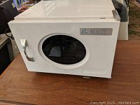 Front view of the white hot cabinet with oval glass window and chrome handle, showing Be Beauty branding.