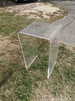 Full view of the clear Lucite stand placed on grass