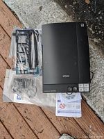 Full view of Epson Perfection V300 Photo flatbed scanner with film and photo holders, software CD, and instruction manual laid out on a surface.