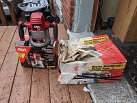 The Skil router sitting on top of its original box next to the damaged router table combo pack box.