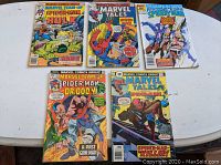 Five Marvel comic books laid out on white table, visible covers include Marvel Team-Up #43 with Dr. Doom, Marvel Tales #71, two Marvel Tales issues (#71 and #79), and Peter Parker The Spectacular Spider-Man #119.