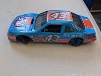 Top angled view of blue diecast NASCAR car model showing number 43 and sponsor decals from the left side.