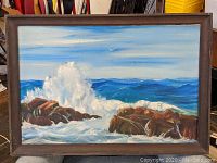 Frontal view of the framed oil painting showing the seascape with crashing waves and rocks.