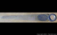 Full view of bronze letter opener with magnifier lens on handle and ruler edge on blade.