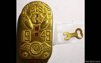 Front view of brass/gold-tone decoder with embossed Captain Midnight S.S. 1949 design and included small key.