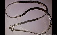 Full view of a 15 inch silver snake scale link necklace laid out flat to show length and design.