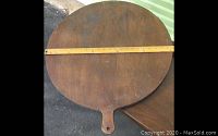 Full view of a round wooden bread or pastry board with handle, showing its size approximately 23 inches diameter including handle.