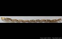 Full length photo of a gold bracelet with rectangular linked design.