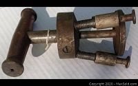 Close-up of the wooden handle, threaded central cylinder, and two of the three spring legs with thumb screws on a white background.