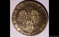 Reverse side of the 1899 British one shilling coin showing three heraldic shields with a crown and the date 1899 along with 'ONE SHILLING' inscription.