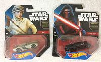 Front view of sealed Hot Wheels Star Wars cars featuring Rey in white and Kylo Ren in black in original packaging.