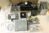 Photo of keyboard, mouse, hard drive, fans, power supply, optical drive, software DVDs and cables laid out on towel.