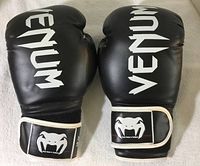 Front view of the pair of black Venum boxing gloves with white logo and wrist strap detail.