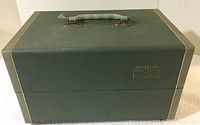 Front view of the Argus Automatic 7 slide storage box showing green cover with logo and handle.