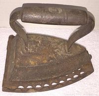 Side view of vintage cast iron sad iron showing aged wooden handle and rusted iron base.