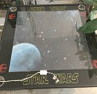 Full view of square Star Wars X Wing custom game table with glass top showing starfield and planetary design, illuminated with lights and foam edging visible.