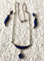Full set showing necklace and earrings on white textured background.