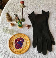 Full view of all items on white textured fabric including gloves, patch, figures, birdhouse, glass knobs