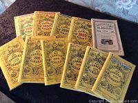 Set of 11 vintage Farmer's Almanacs from the 1970s and 1980s laid out on a surface, showcasing yellow covers and varying years.