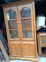 Front view of Keller Furniture china cabinet showing wood grain finish, glass doors with brass handles, and carved solid wood lower doors.