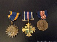 Three WWII military medals displayed front side showing ribbons and medal faces. From left: Soldier's Medal, Distinguished Flying Cross, and Air Medal.