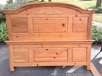 Front view of the knotty pine headboard and footboard together outdoors showing wood grain and decorative carving on headboard.
