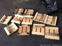 Lot of 11 wooden patio pot caddies arranged on ground; some with wheels attached and some new in boxes.