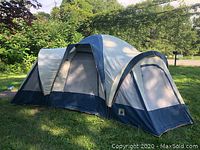 Photo showing side view of large spacious tent with multiple sections and blue base trim