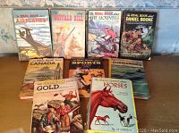 Nine vintage 1952 Real Book series volumes standing on a table against wallpapered background, showing titles.