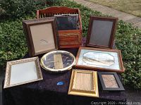 Overall lot view on table outdoors of frames, clock, and cowboy rack