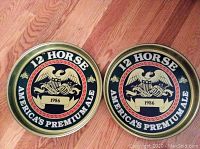 Pair of vintage Genesee 12 Horse Ale metal beer trays, 1986, with American bald eagle design, on wooden floor