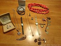 Photo of entire jewelry lot on table including necklaces, bracelets, watches, earrings, pins, and two pieces in Marmel box