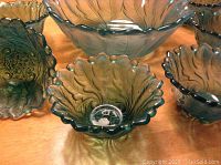 View of the green glass bowls showing scalloped edges and footed bases.